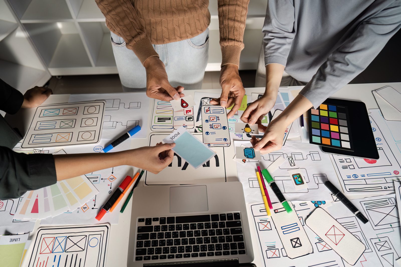 Team collaborating on UX UI design, brainstorming innovative digital interface ideas with sketches and digital tools.